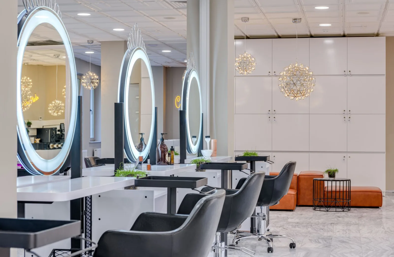 Ein Friseursalon mit runden beleuchteten Spiegeln und schwarzen Stühlen