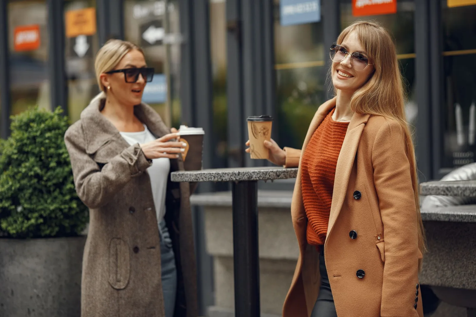 Dos mujeres charlan con un café a la puerta de una cafetería