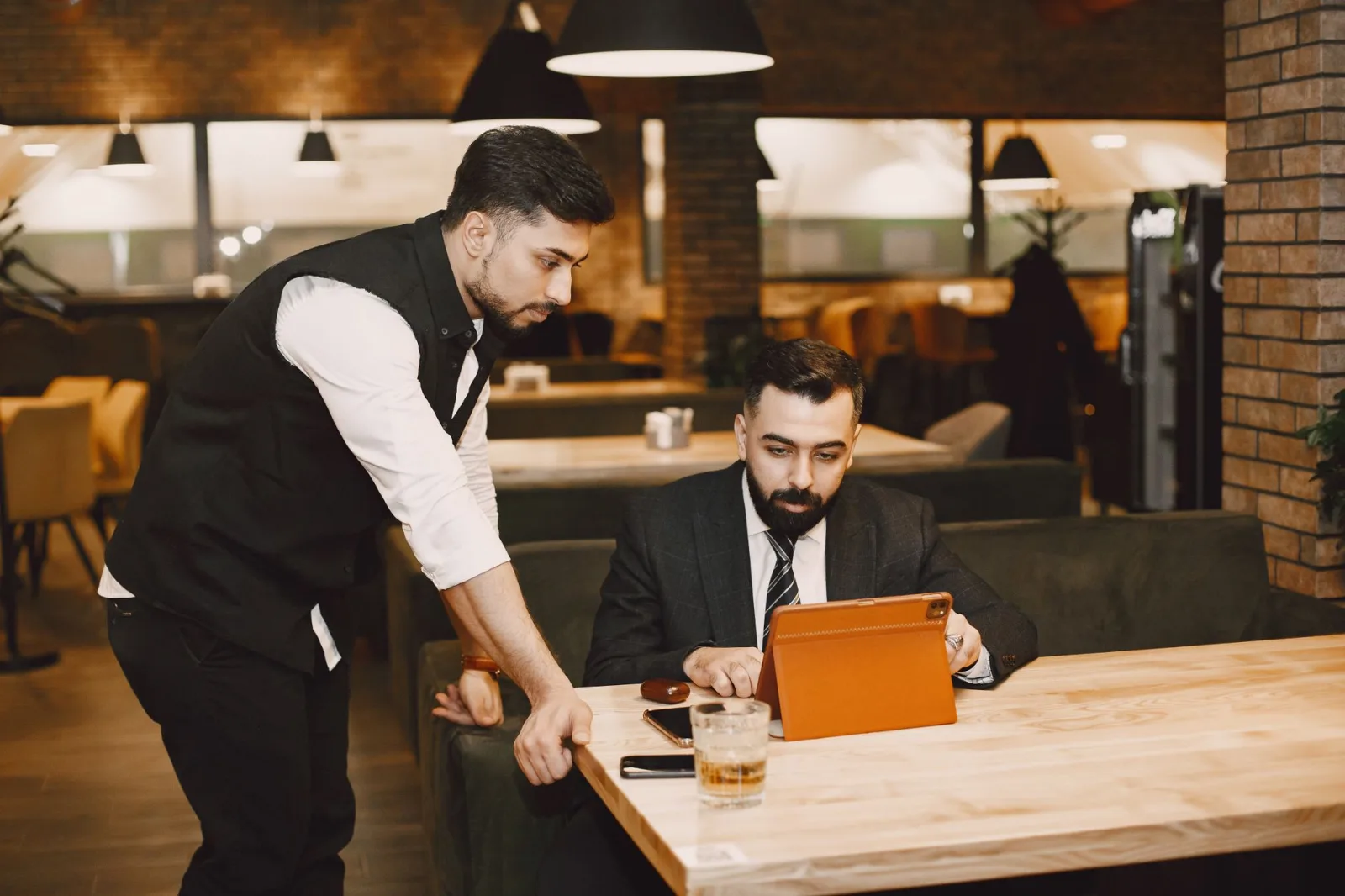 Ein Kellner zeigt einem Gast im Restaurant etwas auf dem Tablet